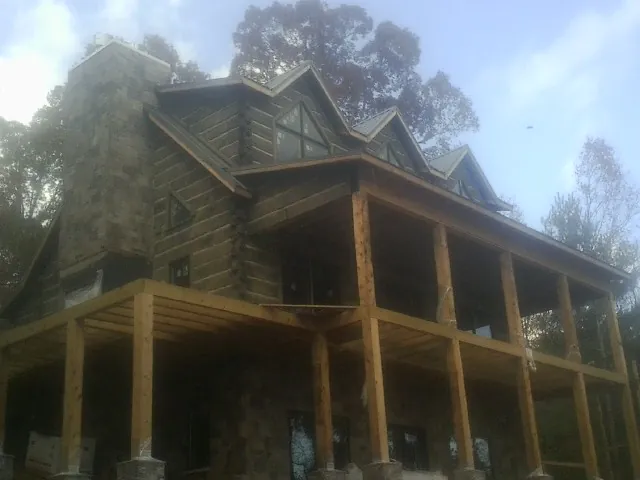 Stone chimney and dormers on a large log home with a timber porch in Warrensburg