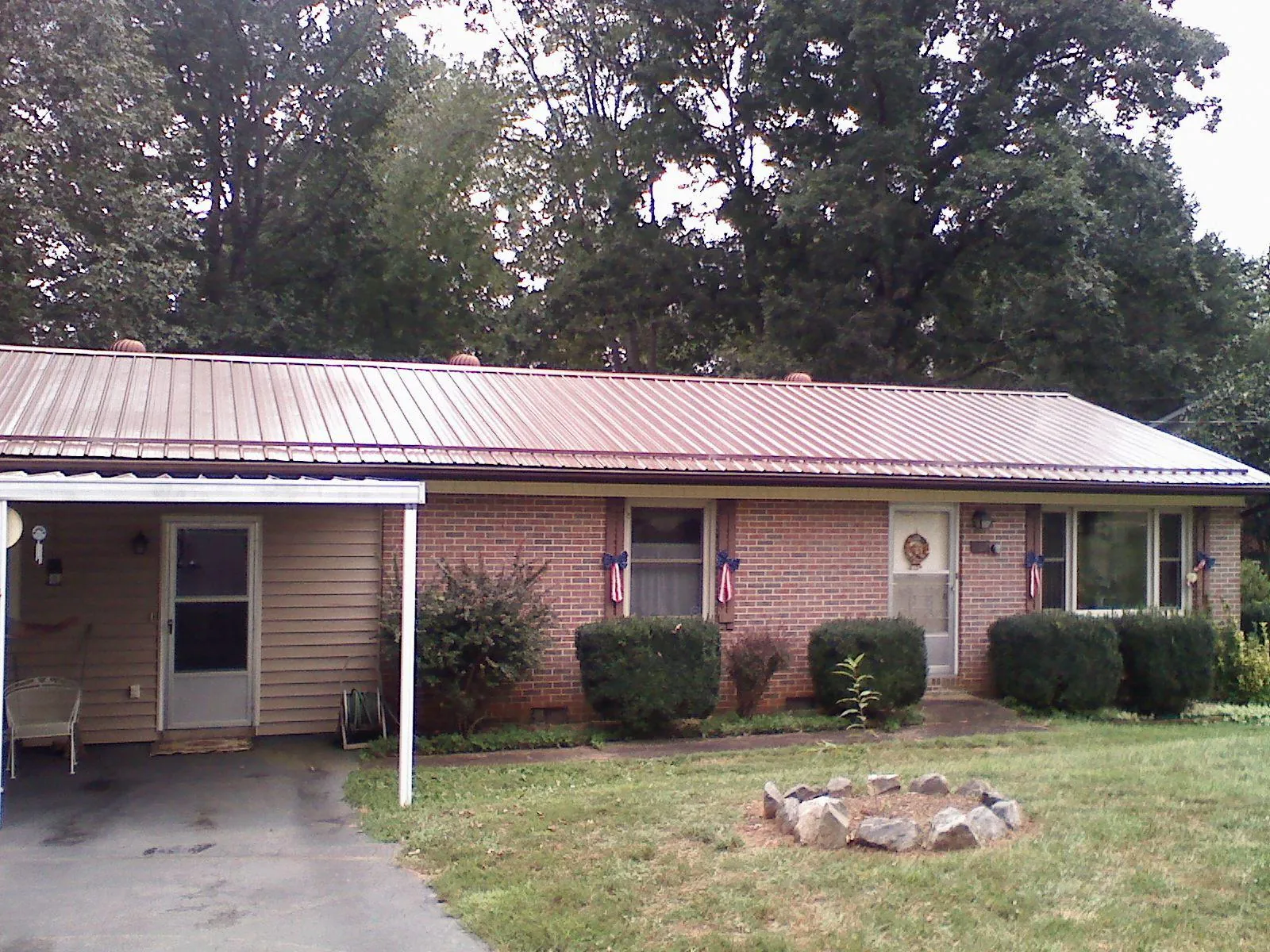 Bronze metal roof and carport on a brick ranch home — Roof Repair work by our crew in Warrensburg